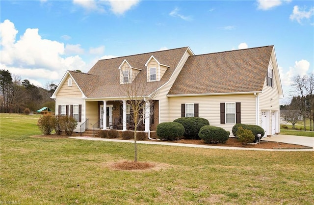 new england style home with covered porch, a garage, and a front lawn