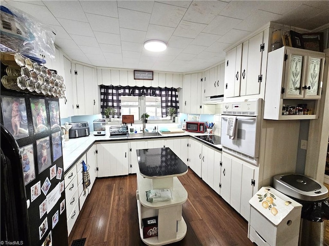 kitchen with sink, oven, white cabinets, and a kitchen island