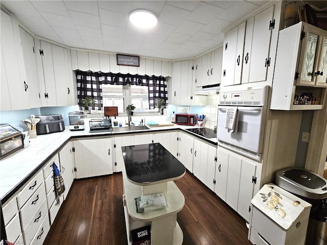 kitchen featuring white cabinetry, a center island, black electric stovetop, and oven