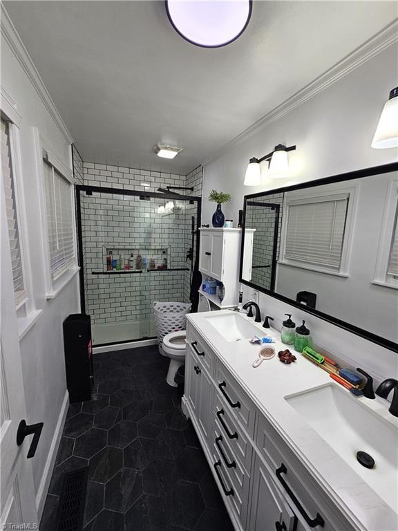 bathroom featuring ornamental molding, toilet, a shower with door, and vanity