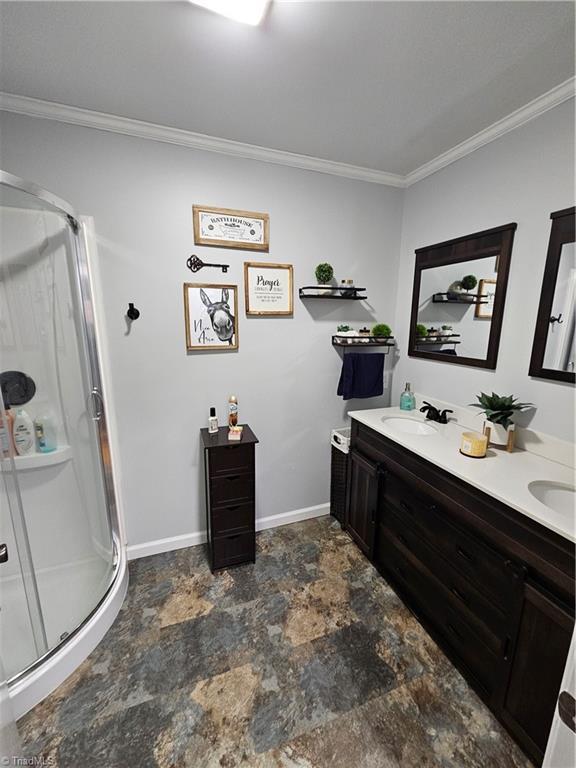 bathroom with vanity, crown molding, and a shower with shower door