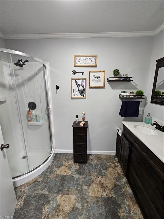 bathroom featuring vanity, crown molding, and walk in shower