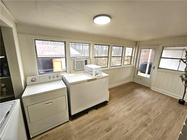 clothes washing area with cooling unit, light hardwood / wood-style flooring, and washer and dryer