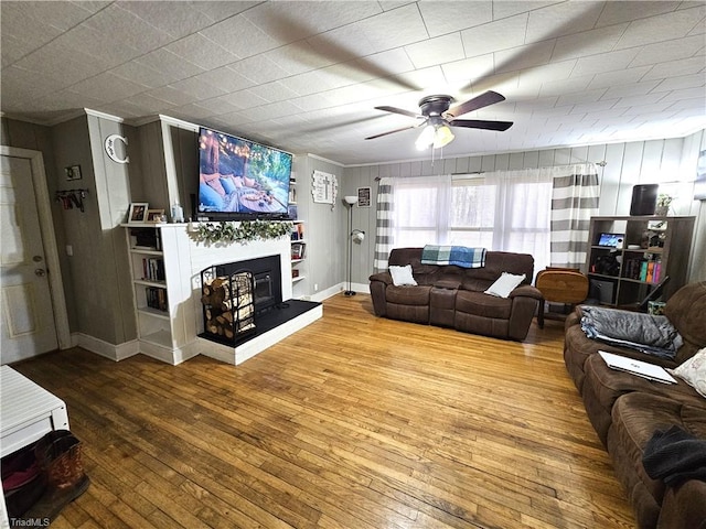 living room featuring hardwood / wood-style floors, ornamental molding, and ceiling fan