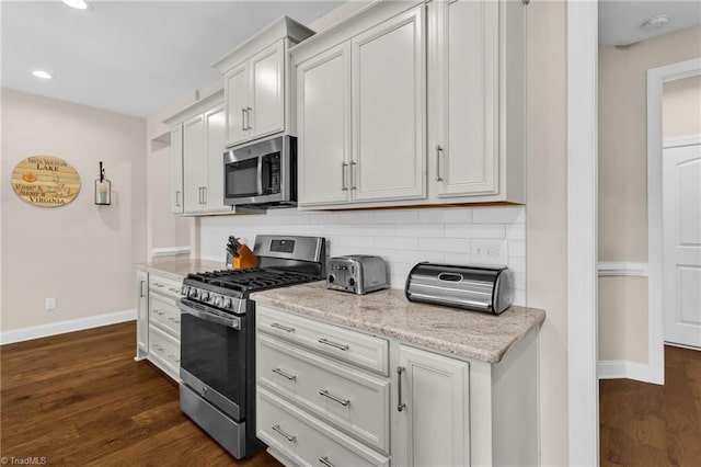 kitchen featuring decorative backsplash, white cabinetry, dark hardwood / wood-style floors, and appliances with stainless steel finishes