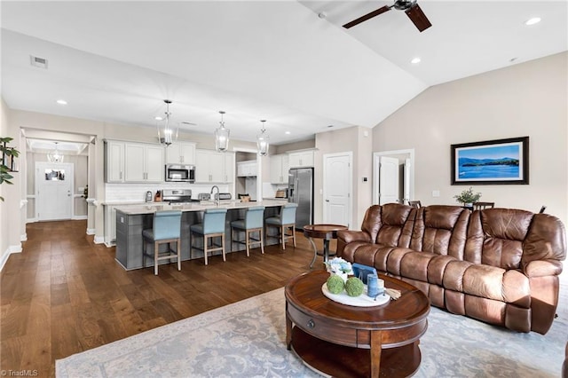 living room with dark hardwood / wood-style flooring, vaulted ceiling, ceiling fan, and sink