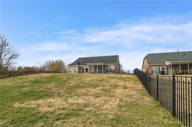 rear view of house featuring a sunroom and a yard