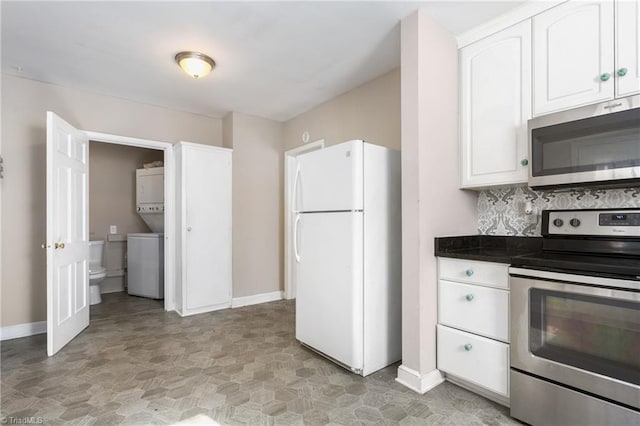 kitchen featuring appliances with stainless steel finishes, stacked washing maching and dryer, white cabinetry, and tasteful backsplash