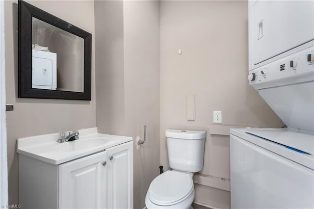 bathroom with stacked washing maching and dryer, vanity, and toilet