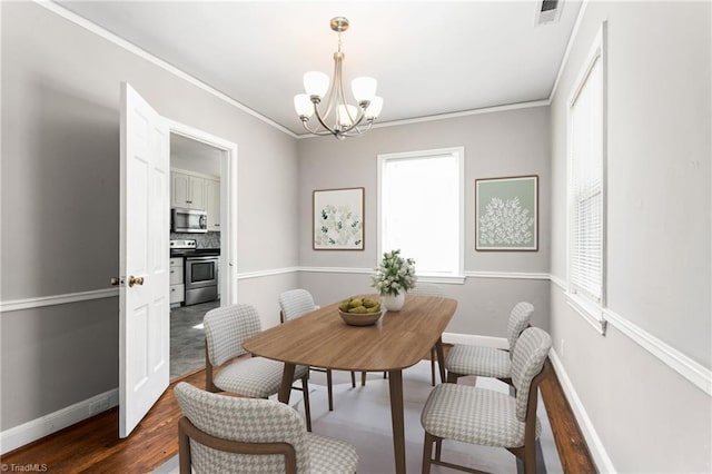 dining room with dark wood-type flooring, a notable chandelier, and crown molding