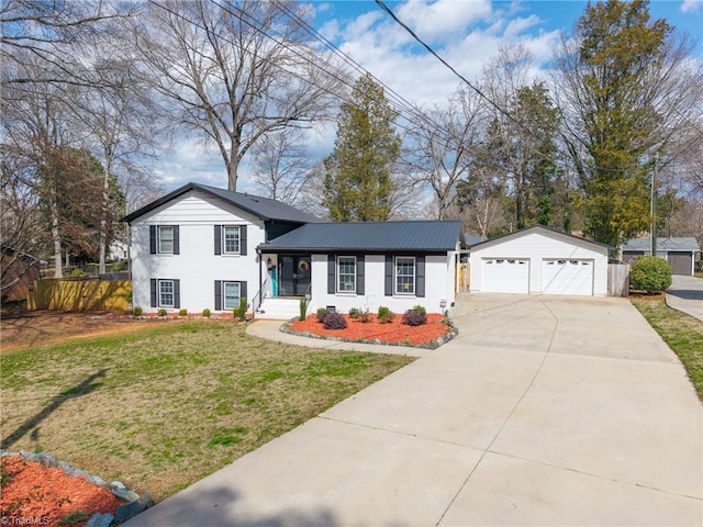 tri-level home with a detached garage, fence, a front yard, and an outdoor structure