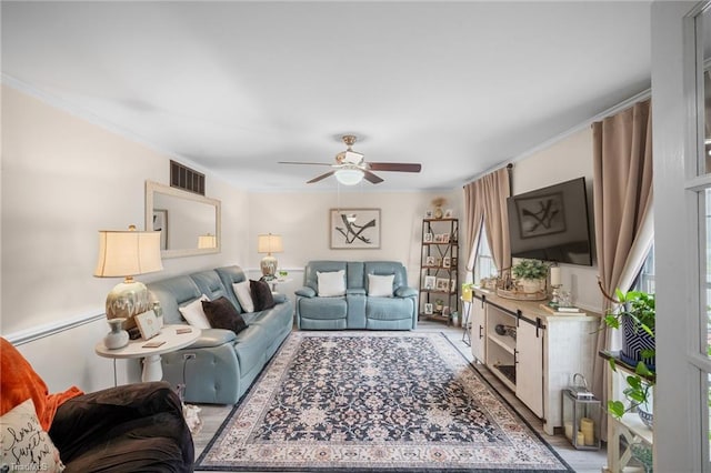 living area featuring visible vents, ceiling fan, and ornamental molding