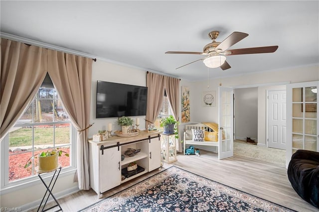 living room featuring baseboards, wood finished floors, ornamental molding, and a ceiling fan