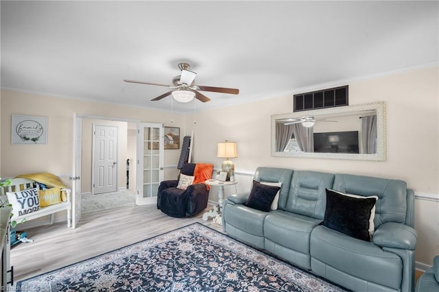 living area featuring wood finished floors, visible vents, ceiling fan, french doors, and crown molding