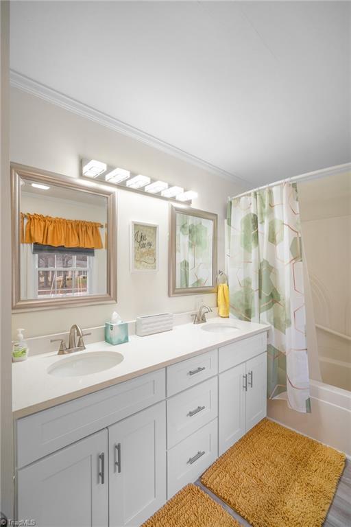 bathroom with a sink, shower / bath combo, ornamental molding, and double vanity