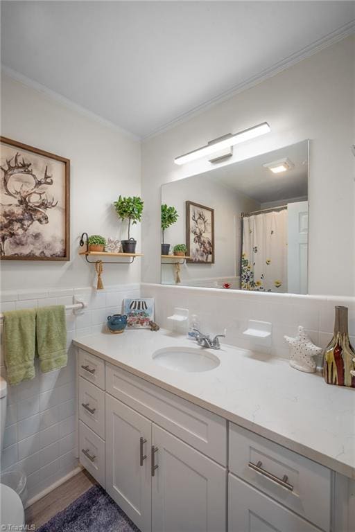 bathroom with toilet, wood finished floors, tile walls, crown molding, and vanity