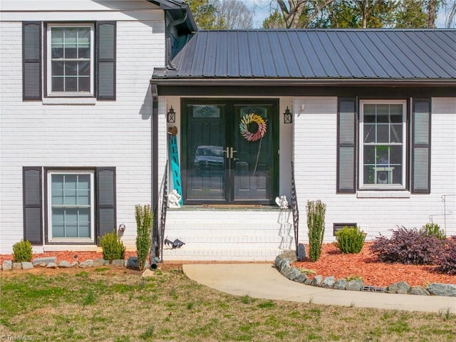 entrance to property with metal roof, brick siding, and french doors