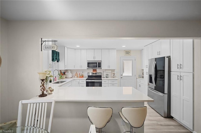 kitchen featuring a breakfast bar, a peninsula, stainless steel appliances, and a sink