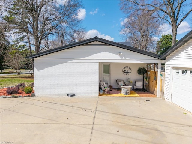 view of side of property with a garage, brick siding, and concrete driveway