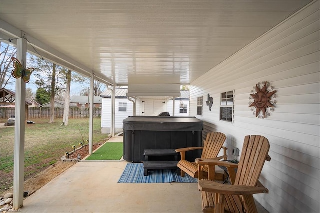 view of patio with an outbuilding, fence, and a hot tub