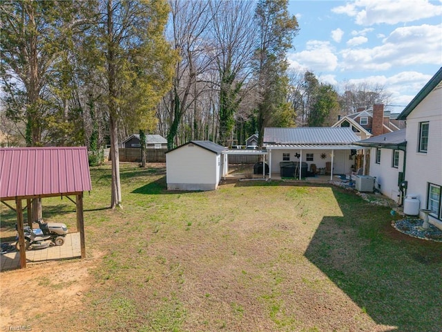 view of yard with an outbuilding, fence, central AC, a storage shed, and a patio area