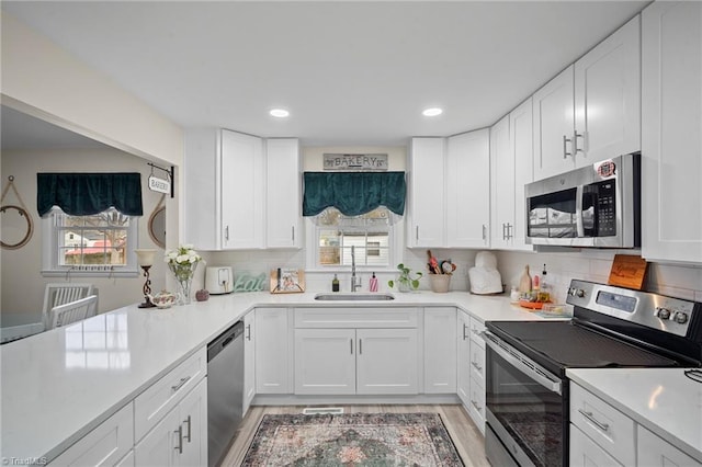 kitchen with a sink, white cabinetry, appliances with stainless steel finishes, and light countertops