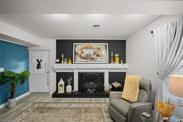 sitting room featuring a brick fireplace, baseboards, and wood finished floors