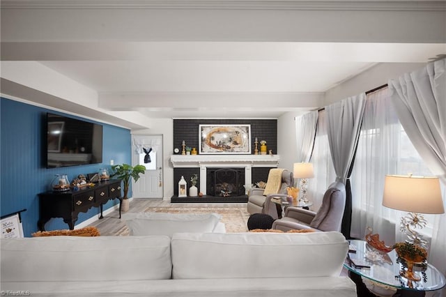 living room featuring beamed ceiling, wood finished floors, and a fireplace with raised hearth