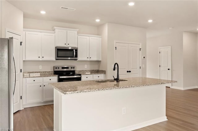 kitchen featuring a center island with sink, white cabinets, sink, appliances with stainless steel finishes, and light hardwood / wood-style floors