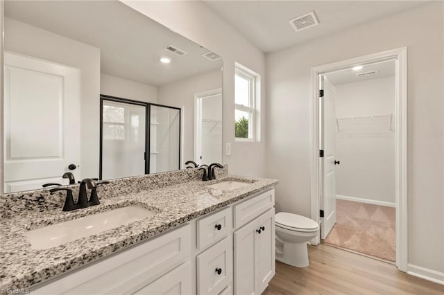 bathroom with toilet, vanity, a shower with shower door, and hardwood / wood-style flooring