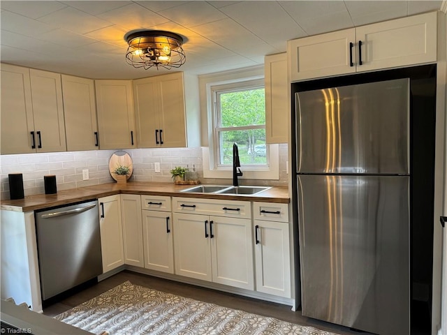 kitchen with decorative backsplash, a sink, stainless steel appliances, white cabinetry, and dark wood-type flooring