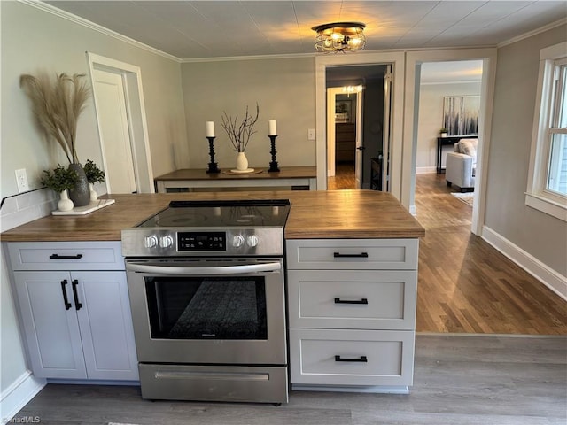 interior space featuring crown molding, baseboards, electric range, and wood finished floors