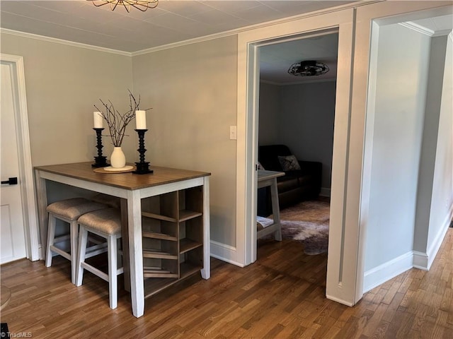 hallway featuring baseboards, ornamental molding, and wood finished floors