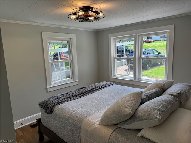bedroom featuring baseboards, ornamental molding, and wood finished floors