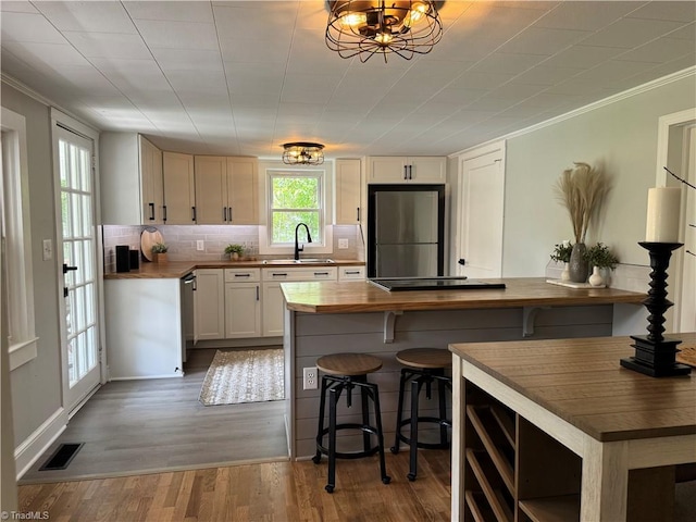kitchen featuring visible vents, wood finished floors, a sink, wood counters, and stainless steel appliances
