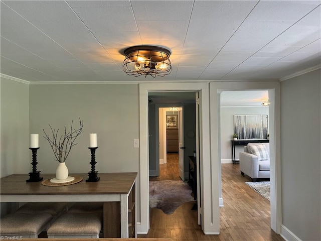 hall with baseboards, ornamental molding, and wood finished floors