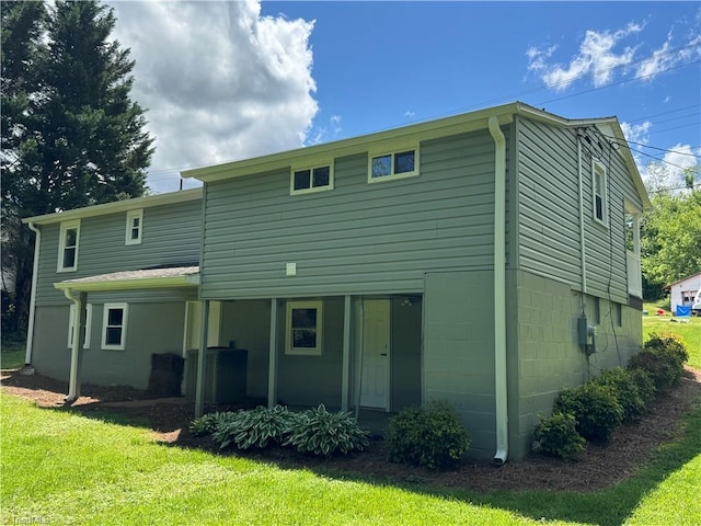 back of house with central air condition unit and a yard