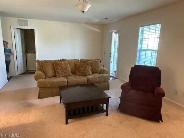 living room with light colored carpet and washer / clothes dryer