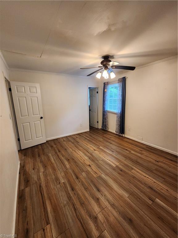 1129 Foxtrot Ct, King, NC 27021 - spare room featuring dark wood-style flooring, a ceiling fan, baseboards, and crown molding