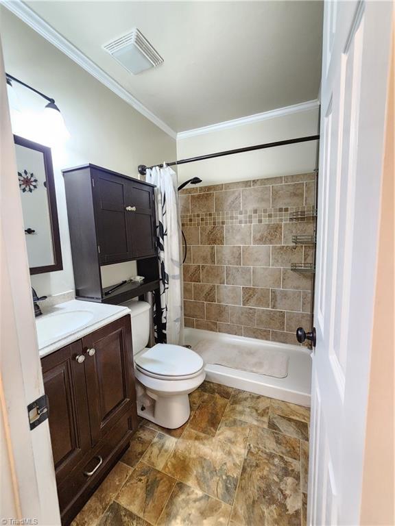 1129 Foxtrot Ct, King, NC 27021 - full bathroom with ornamental molding, toilet, vanity, tiled shower, and stone finish floors