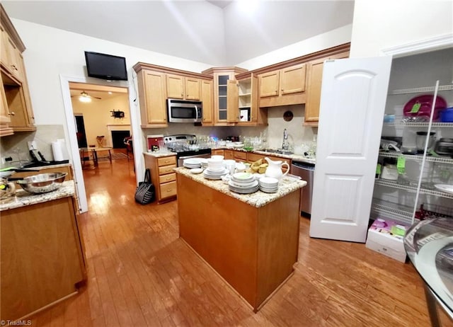 kitchen featuring stainless steel appliances, a kitchen island, sink, and light hardwood / wood-style flooring