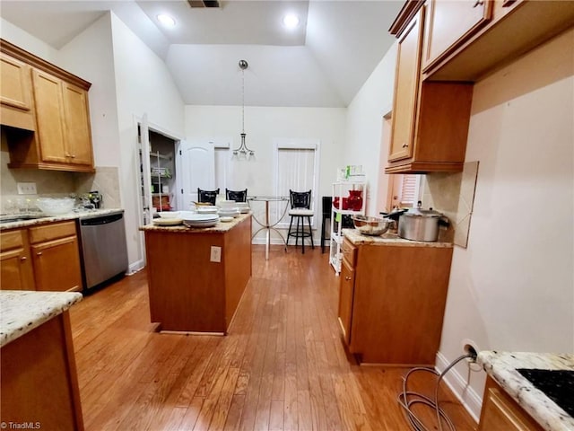 kitchen with decorative backsplash, a kitchen island, decorative light fixtures, stainless steel dishwasher, and light wood-type flooring