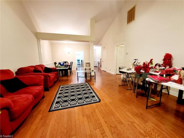 living room with hardwood / wood-style flooring, decorative columns, and a high ceiling