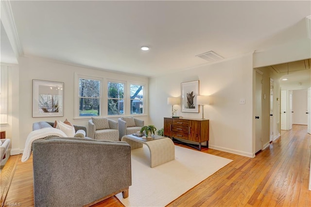 living room with ornamental molding and light hardwood / wood-style flooring