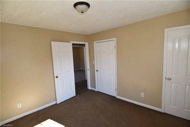 unfurnished bedroom with a textured ceiling and dark colored carpet