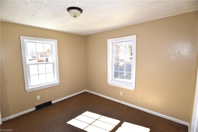 carpeted empty room featuring a textured ceiling