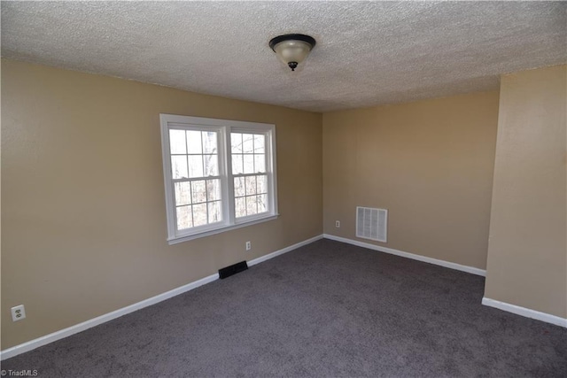 empty room featuring dark carpet and a textured ceiling