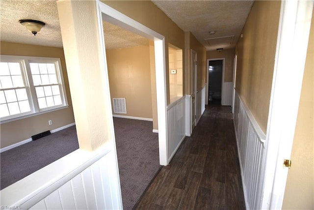 hallway with dark hardwood / wood-style floors and a textured ceiling