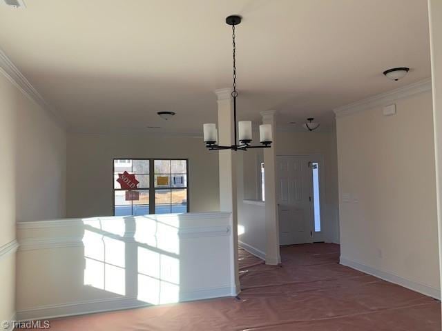 unfurnished room with ornamental molding, a notable chandelier, and baseboards