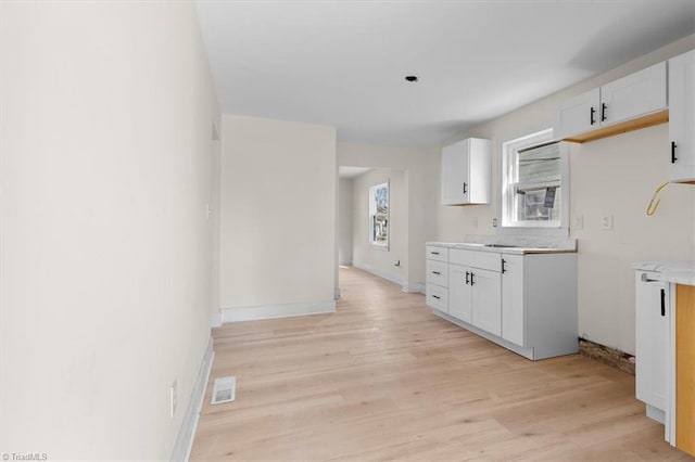 kitchen with light hardwood / wood-style flooring and white cabinets